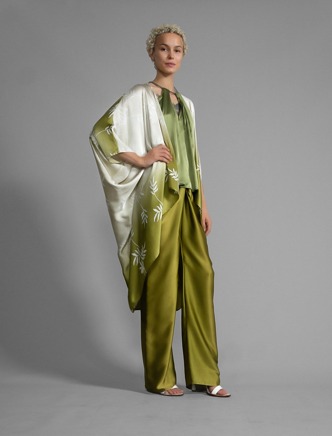 Right side. Relaxed flowing silk kaftan with subtle Dedaun leaf motif in moss green and white colour, featuring 3/4 length sleeves and a voluminous silhouette.
