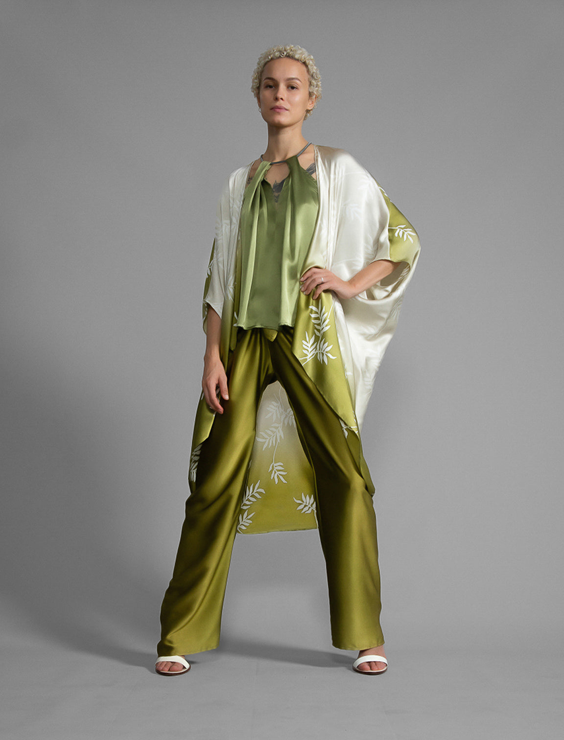 Left side. Relaxed flowing silk kaftan with subtle Dedaun leaf motif in moss green and white colour, featuring 3/4 length sleeves and a voluminous silhouette.
