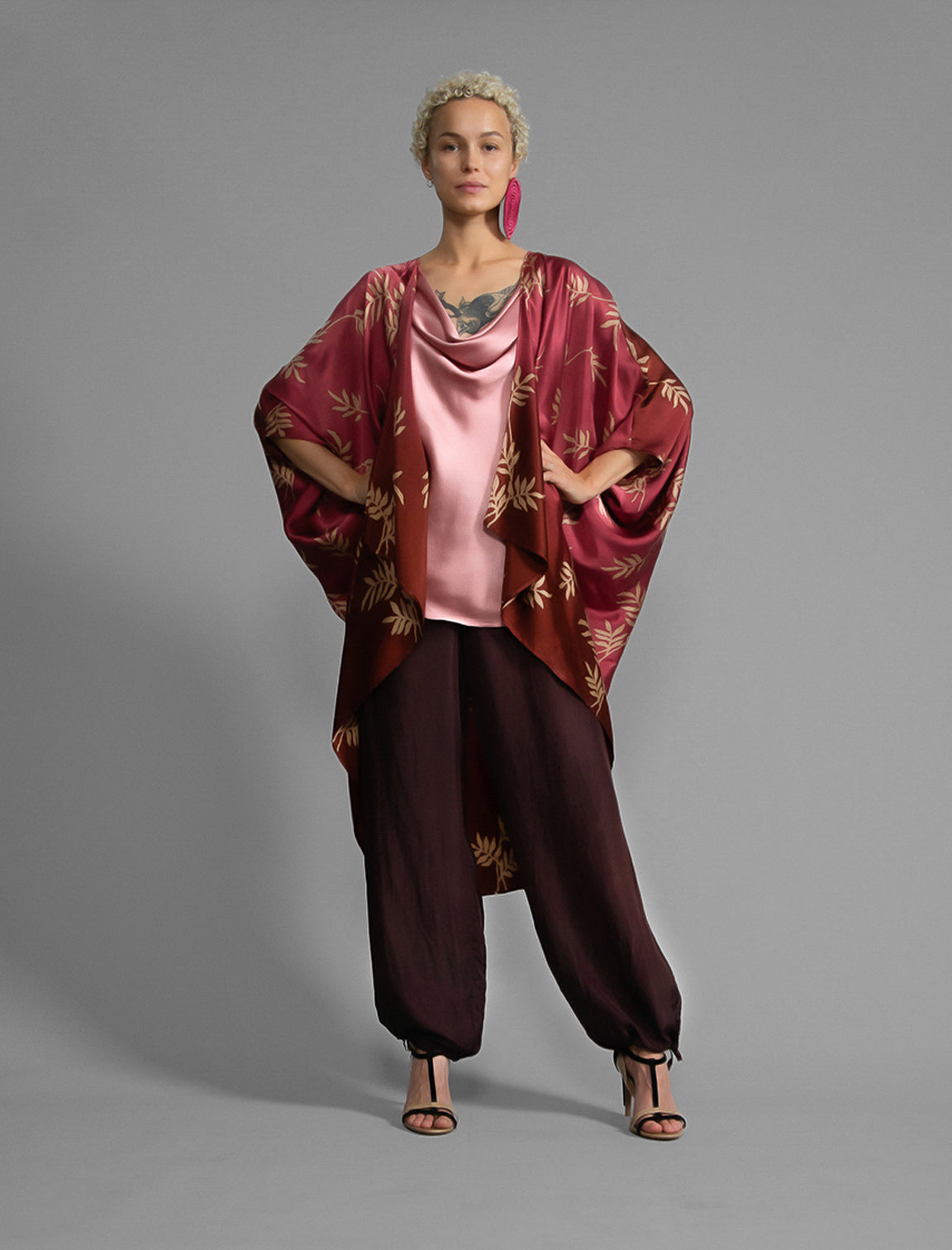 Front view. Relaxed flowing silk kaftan with subtle Dedaun leaf motif in russet and raspberry colour, featuring 3/4 length sleeves and a voluminous silhouette.