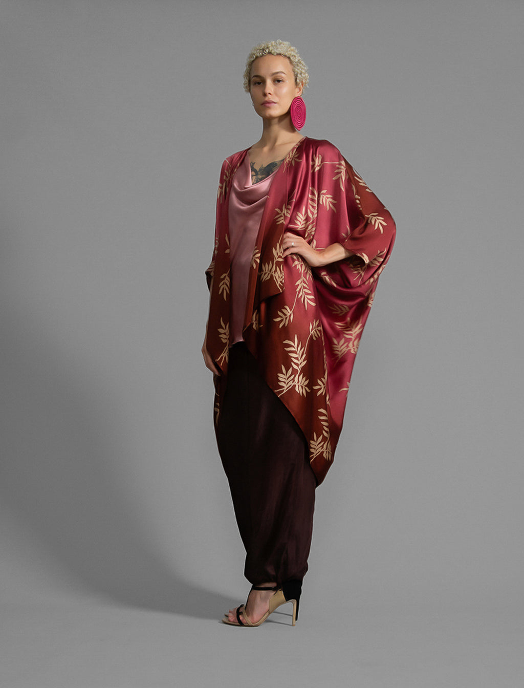 Left side view. Relaxed flowing silk kaftan with subtle Dedaun leaf motif in russet and raspberry colour, featuring 3/4 length sleeves and a voluminous silhouette.