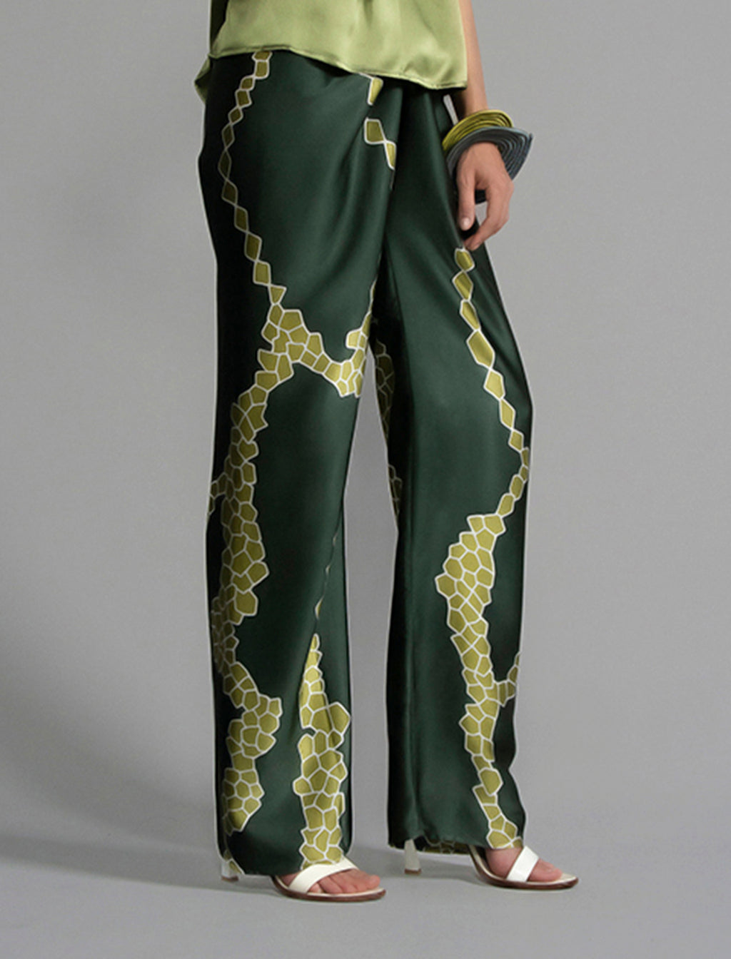 Close front view. Long silk pants in forest green colour with contrasting green graphic Macrosnake batik motif, featuring a knot tie at the front and a slick relaxed silhouette. 