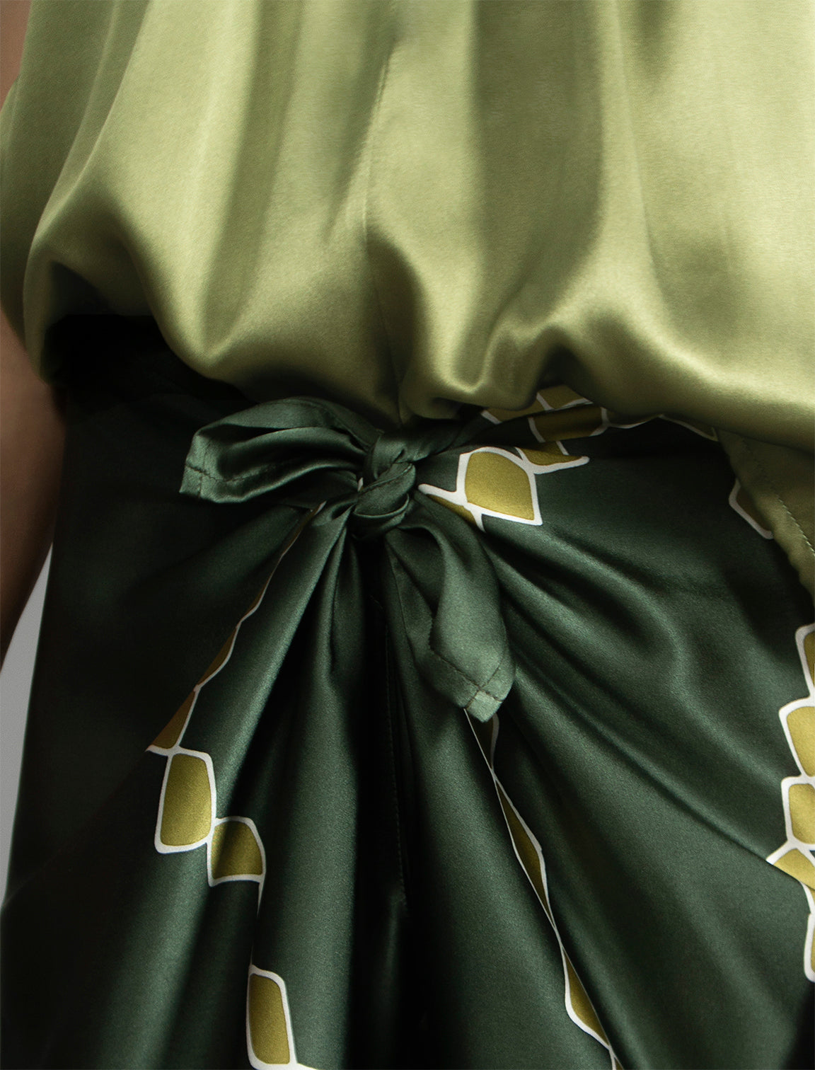 Knot detail. Long silk pants in forest green colour with contrasting blue graphic Macrosnake batik motif, featuring a knot tie at the front and a slick relaxed silhouette. 
