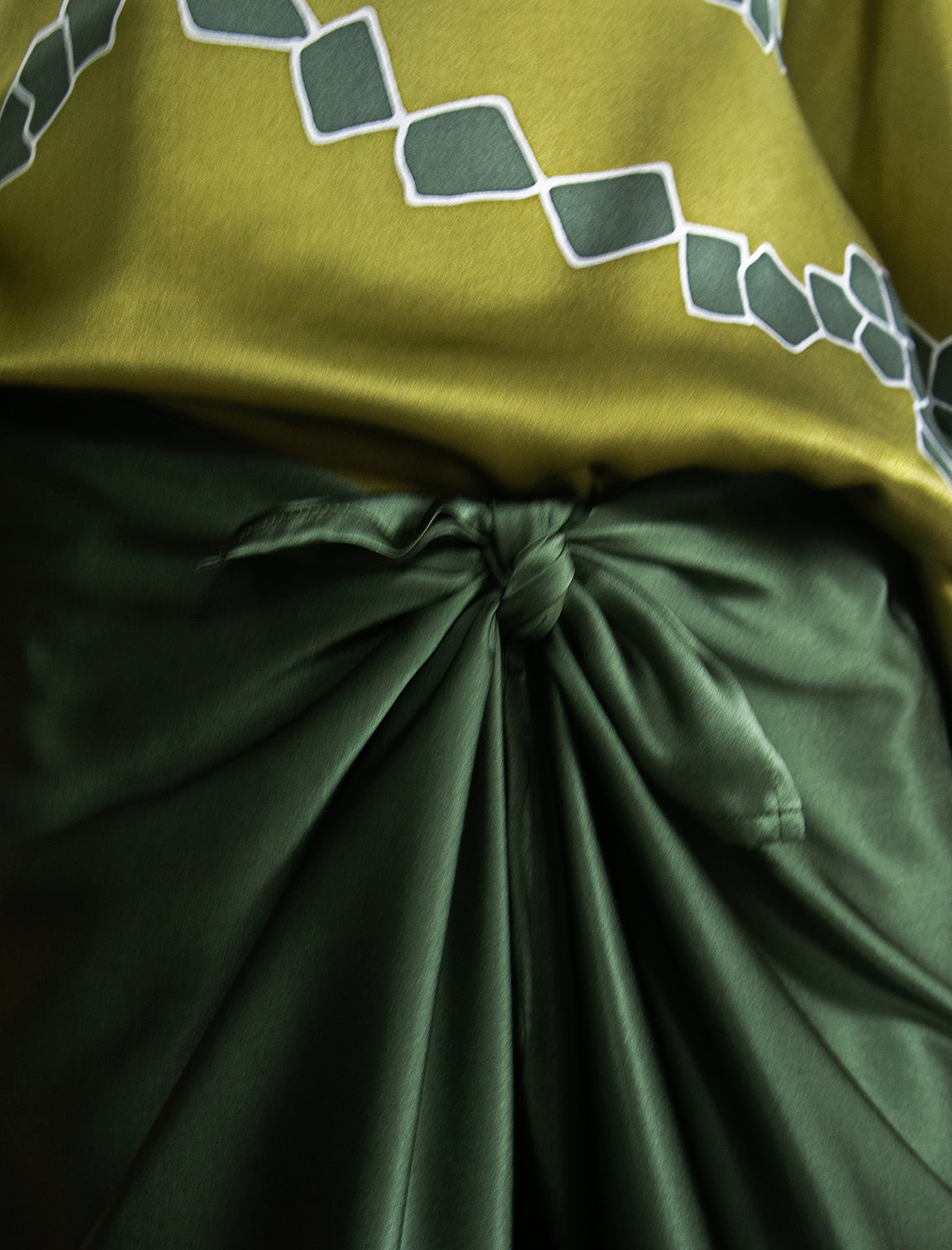 Knot detail: Long silk pants in black forest green colour, featuring a knot tie at the front and a slick relaxed silhouette. 