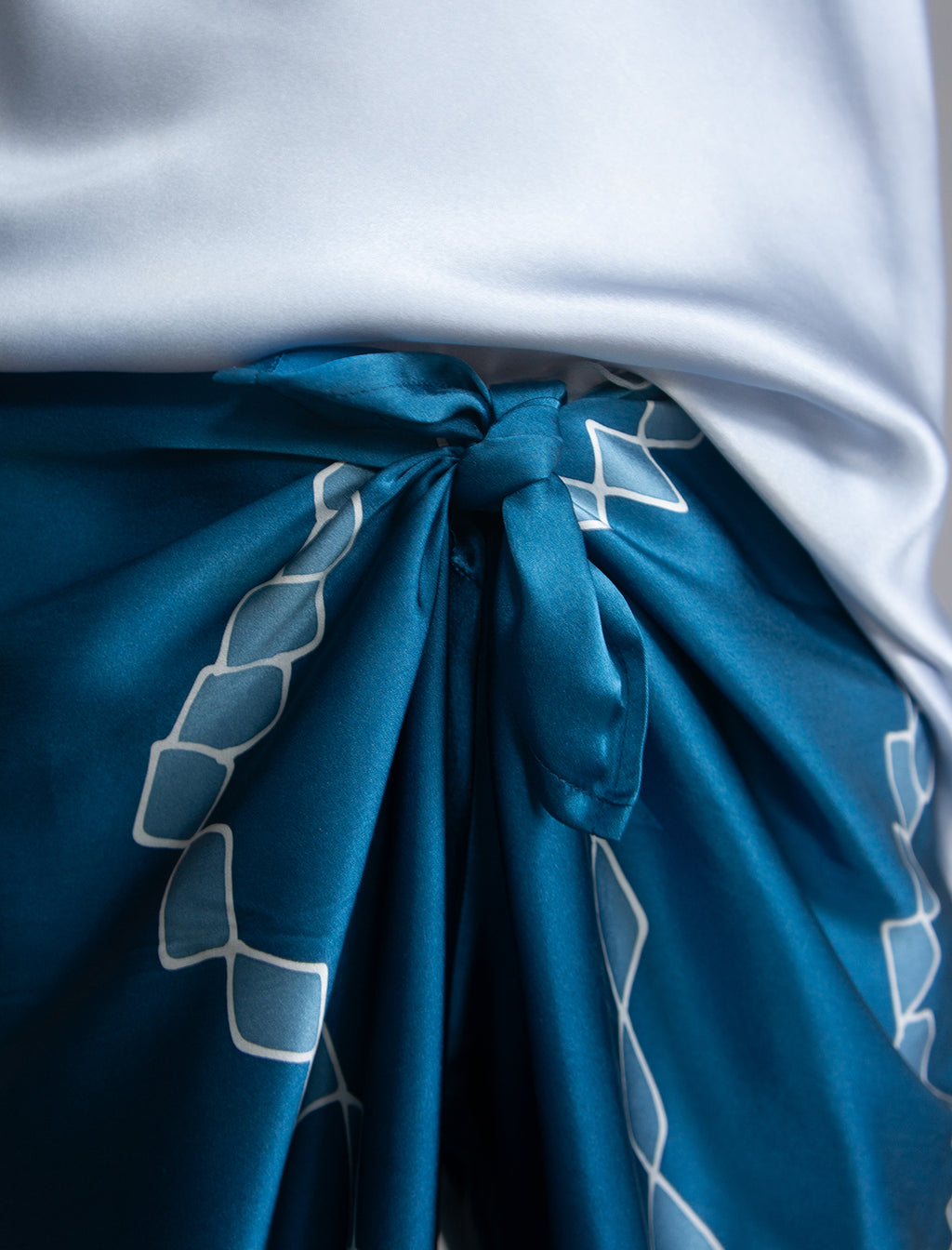 Knot detail: Long silk pants in saxony blue colour with contrasting blue graphic Macrosnake batik motif, featuring a knot tie at the front and a slick relaxed silhouette. 