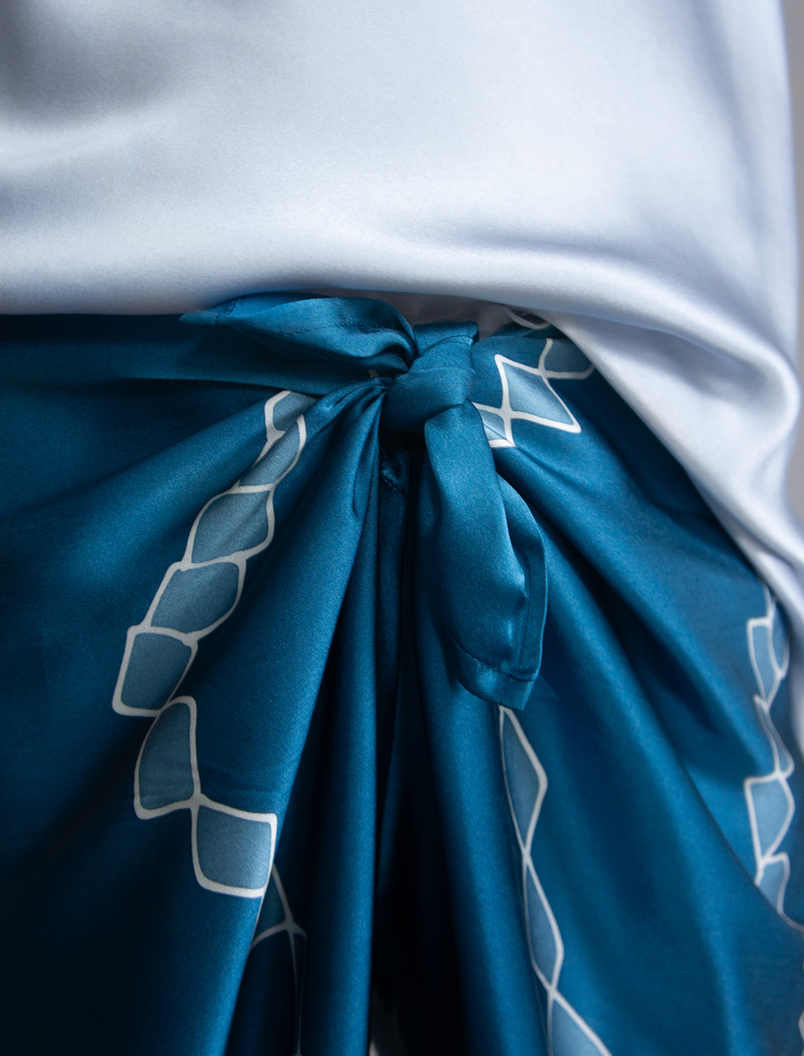 Knot detail: Long silk pants in saxony blue colour with contrasting blue graphic Macrosnake batik motif, featuring a knot tie at the front and a slick relaxed silhouette. 