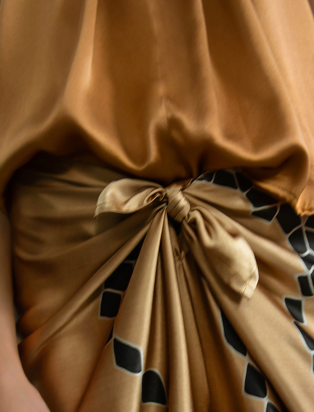 Knot detail: Long silk pants in tobacco colour with black graphic Macrosnake batik motif, featuring a knot tie at the front and a slick relaxed silhouette. 