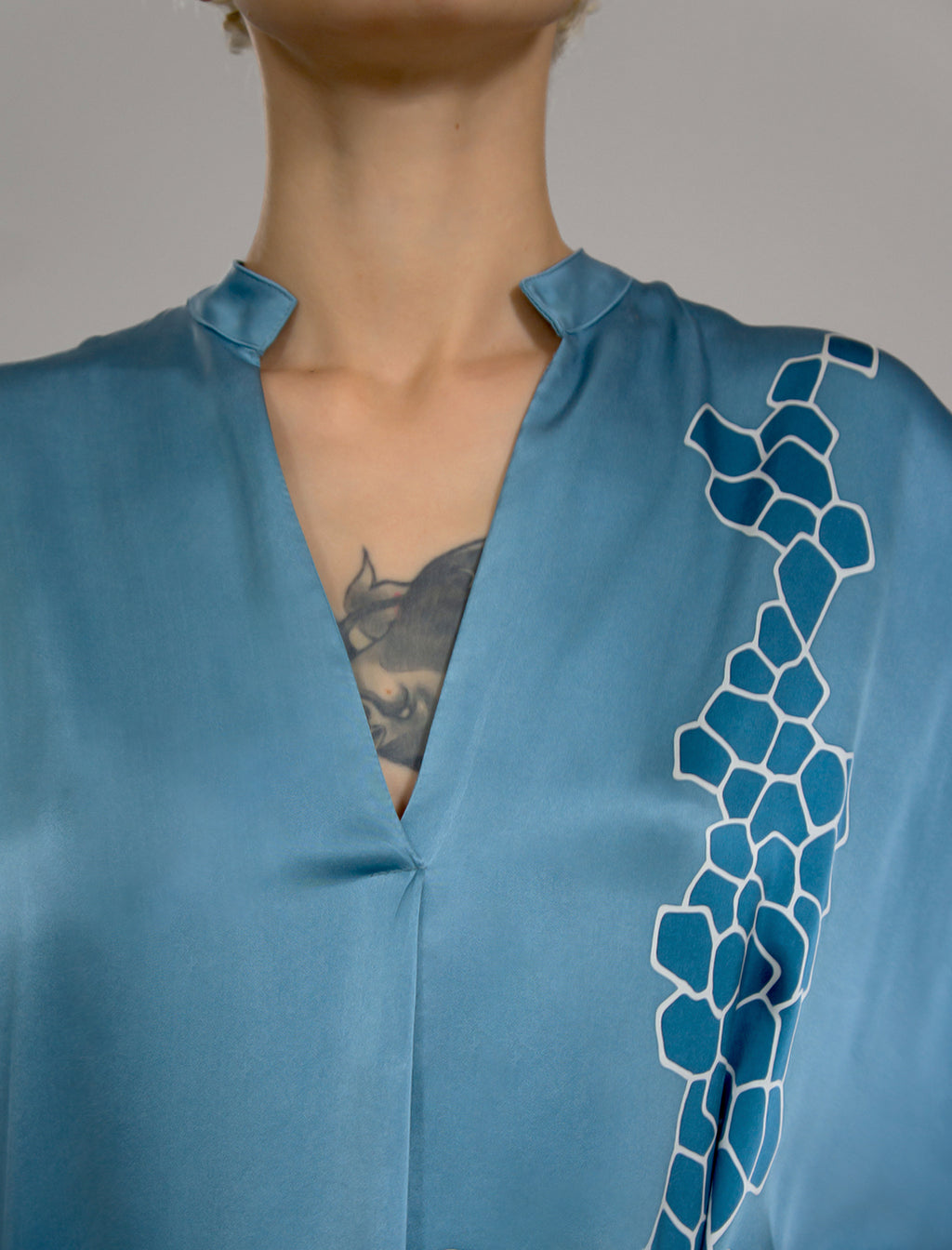 Neckline detail: Mid length shirt dress in dream blue colour with contrasting blue graphic Macrosnake batik motif, featuring short sleeves with deep hem, curved hemline, simple collar with narrow V-neckline and relaxed contemporary silhouette.