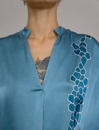 Neckline detail: Mid length shirt dress in dream blue colour with contrasting blue graphic Macrosnake batik motif, featuring short sleeves with deep hem, curved hemline, simple collar with narrow V-neckline and relaxed contemporary silhouette.