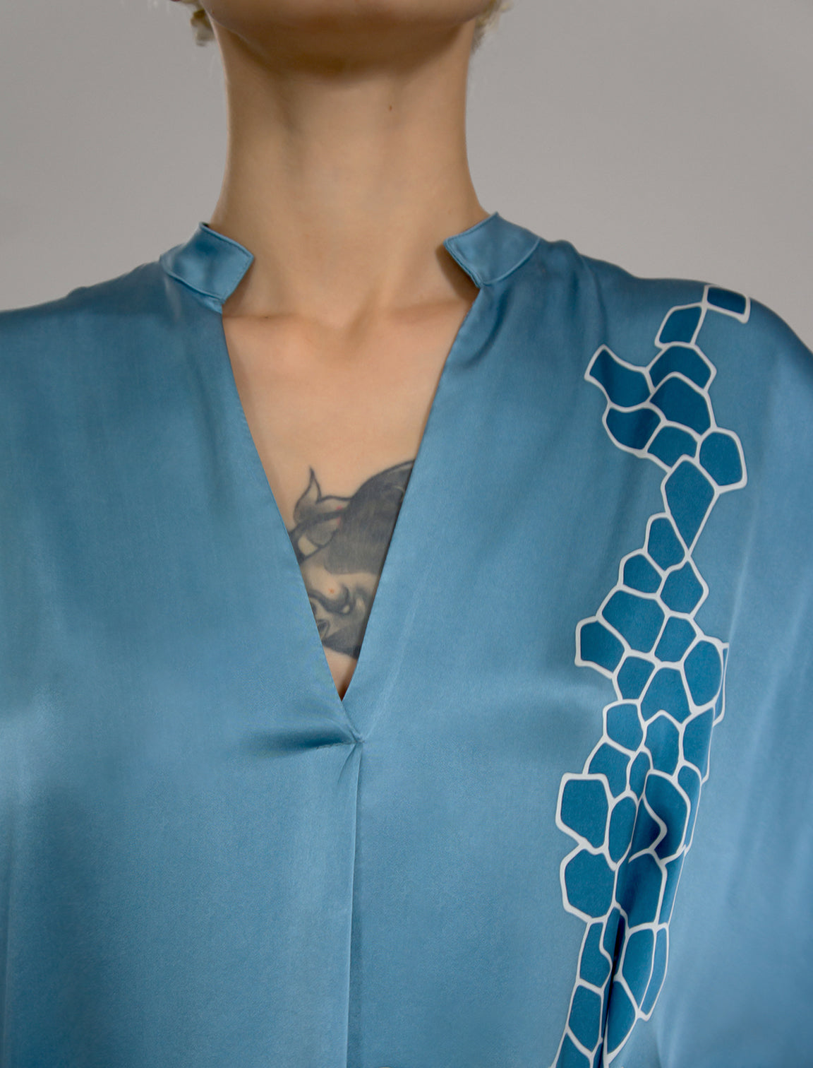 Neckline detail: Mid length shirt dress in dream blue colour with contrasting blue graphic Macrosnake batik motif, featuring short sleeves with deep hem, curved hemline, simple collar with narrow V-neckline and relaxed contemporary silhouette.