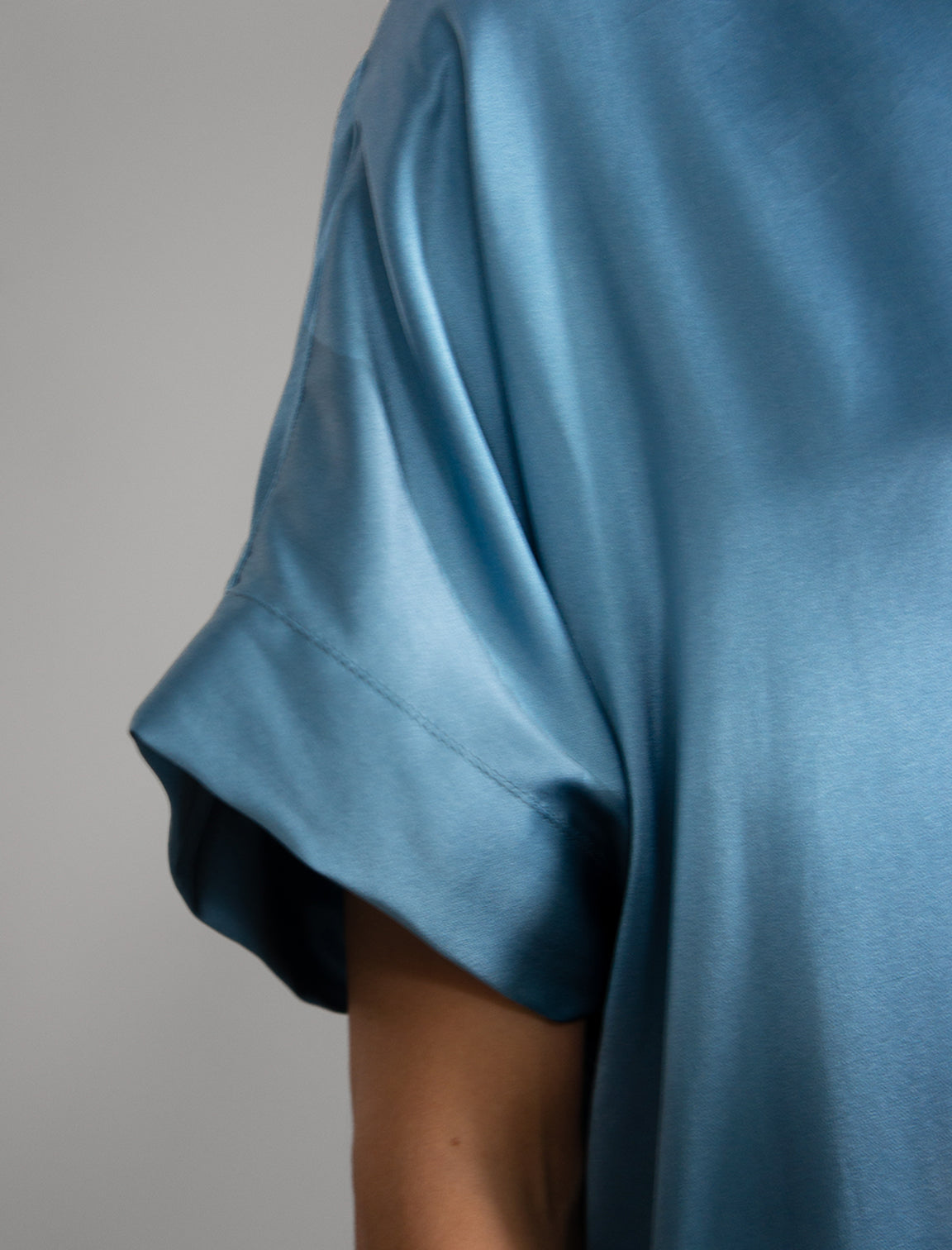 Right sleeve detail: Mid length shirt dress in dream blue colour with contrasting blue graphic Macrosnake batik motif, featuring short sleeves with deep hem, curved hemline, simple collar with narrow V-neckline and relaxed contemporary silhouette.