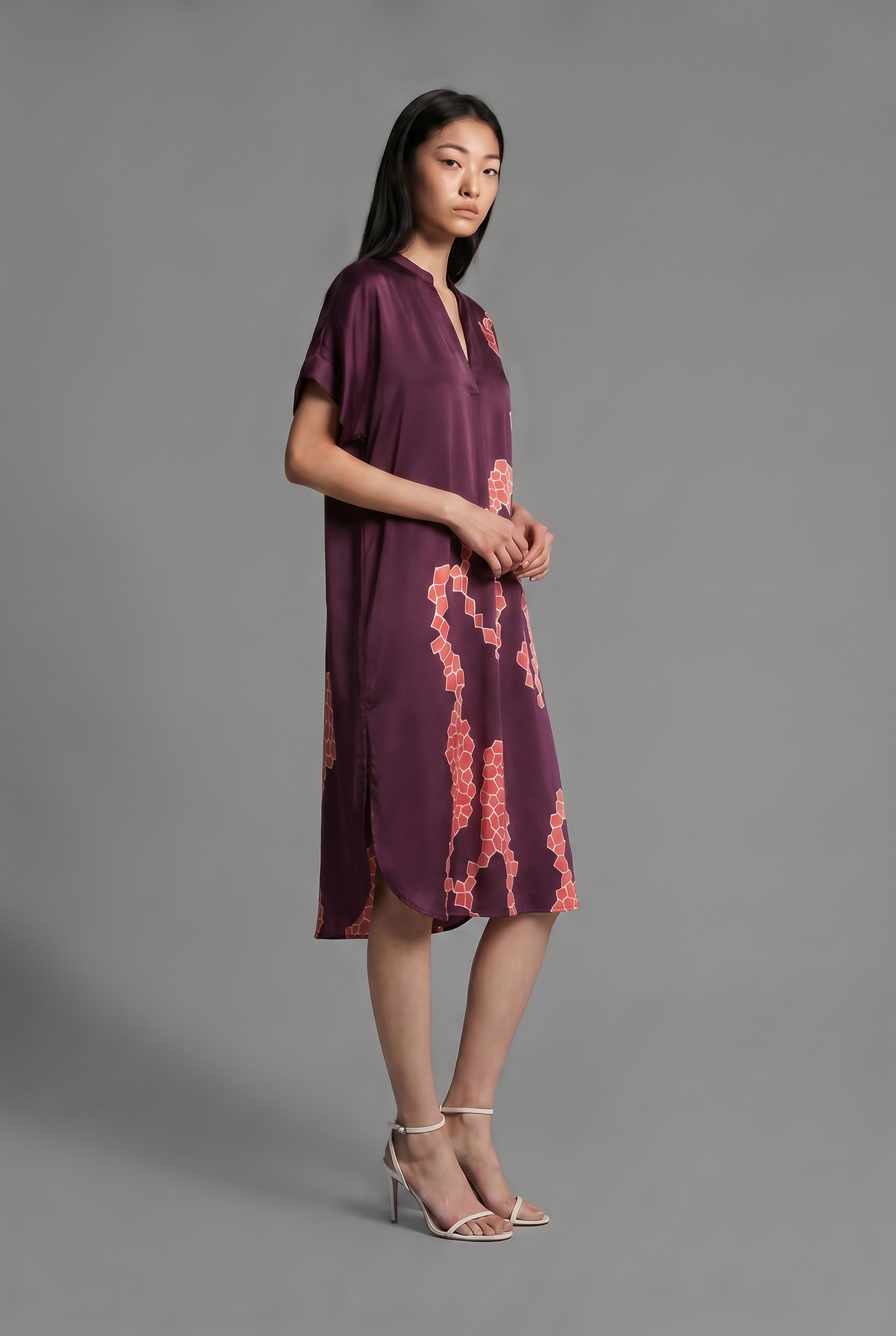 Right side view. Mid length shirt dress in deep vino colour with contrasting bright pink graphic Macrosnake batik motif, featuring short sleeves with deep hem, curved hemline, simple collar with narrow V-neckline and relaxed contemporary silhouette.
