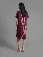 Back view. Mid length shirt dress in deep vino colour with contrasting bright pink graphic Macrosnake batik motif, featuring short sleeves with deep hem, curved hemline, simple collar with narrow V-neckline and relaxed contemporary silhouette.