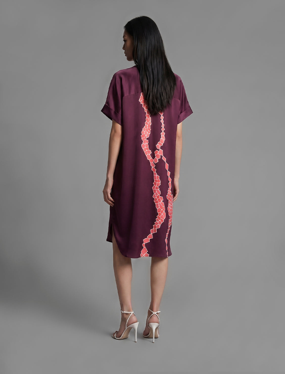 Back view. Mid length shirt dress in deep vino colour with contrasting bright pink graphic Macrosnake batik motif, featuring short sleeves with deep hem, curved hemline, simple collar with narrow V-neckline and relaxed contemporary silhouette.