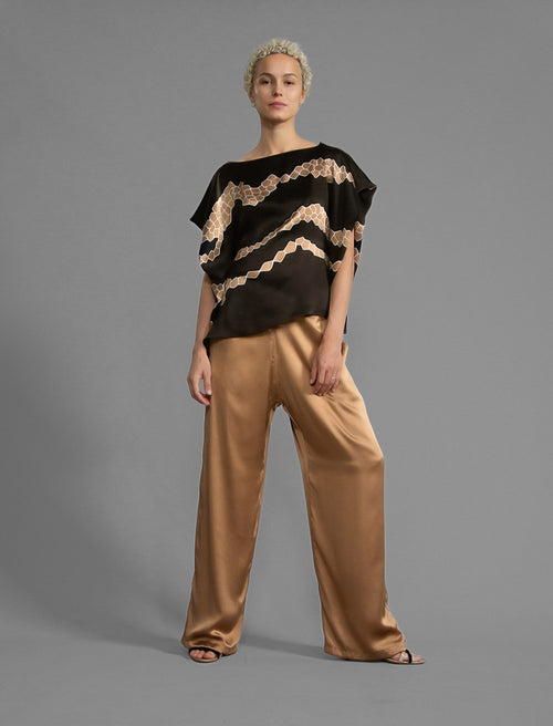 Short sleeve view. Flowing coffee colour silk top with graphic Macrosnake batik motif in warm beige tones, featuring fluid draped sleeves, asymmetrical hemline, and versatile contemporary silhouette designed to be worn three ways.