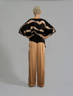 Back view. Flowing coffee colour silk top with graphic Macrosnake batik motif in warm beige tones, featuring fluid draped sleeves, asymmetrical hemline, and versatile contemporary silhouette designed to be worn three ways.