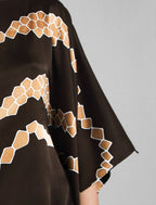 Sleeve detail. Flowing coffee colour silk top with graphic Macrosnake batik motif in warm beige tones, featuring fluid draped sleeves, asymmetrical hemline, and versatile contemporary silhouette designed to be worn three ways.