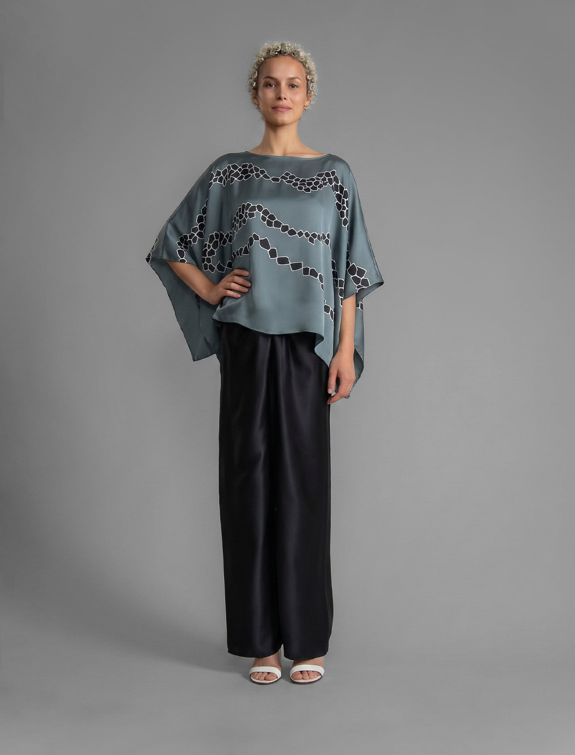 Full sleeve view. Flowing steel grey colour silk top with graphic Macrosnake batik motif in contrasting black, featuring fluid draped sleeves, asymmetrical hemline, and versatile contemporary silhouette designed to be worn three ways.