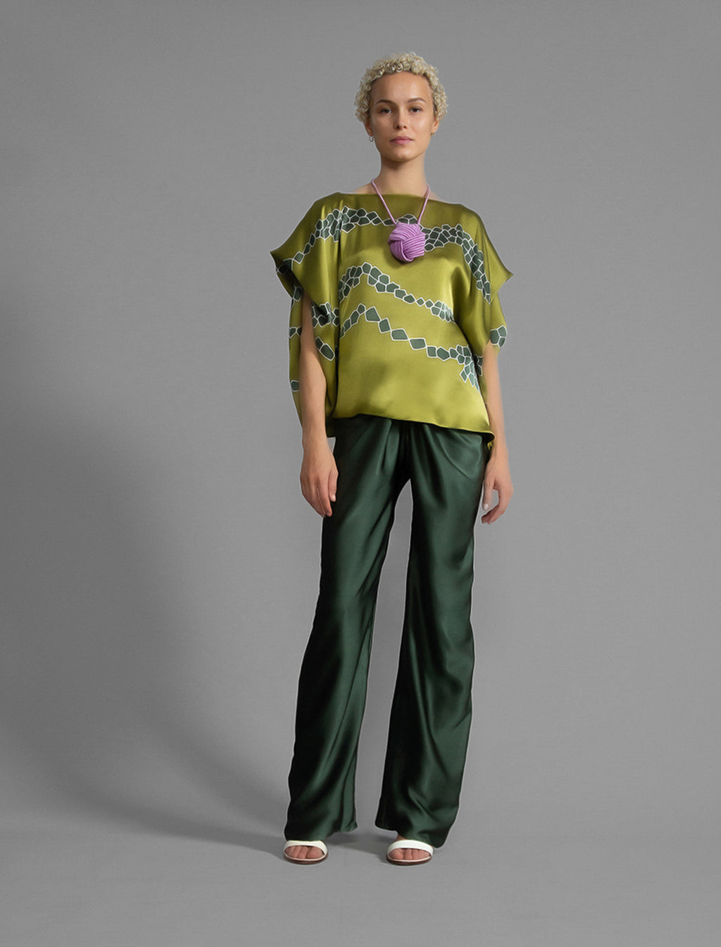 Variation 2. Flowing moss green colour silk top with graphic Macrosnake batik motif in contrasting green tone, featuring fluid draped sleeves, asymmetrical hemline, and versatile contemporary silhouette designed to be worn three ways.
