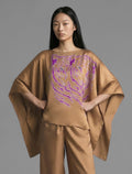 Front view. Flowing tobacco colour silk top with graphic Tiger batik motif in contrasting purple, featuring fluid draped sleeves, asymmetrical hemline, and versatile contemporary silhouette designed to be worn three ways.