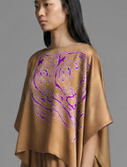 Motif detail. Flowing tobacco colour silk top with graphic Tiger batik motif in contrasting purple, featuring fluid draped sleeves, asymmetrical hemline, and versatile contemporary silhouette designed to be worn three ways.