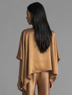 Back view. Flowing tobacco colour silk top with graphic Tiger batik motif in contrasting purple, featuring fluid draped sleeves, asymmetrical hemline, and versatile contemporary silhouette designed to be worn three ways.