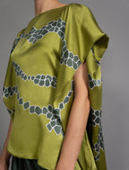 Short sleeve detail: Flowing moss green colour silk top with graphic Macrosnake batik motif in contrasting green tone, featuring fluid draped sleeves, asymmetrical hemline, and versatile contemporary silhouette designed to be worn three ways.
