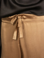Drawstring detail: Relaxed wide-leg silk trousers in warm tobacco, featuring drawstring waistband, elasticated at the back. Soft gathered drape, fluid silhouette, and subtle lustrous finish.