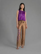 Front view. Long silk pants in tobacco colour with purple tiger head batik motif, featuring a knot tie at the front and a slick relaxed silhouette. 