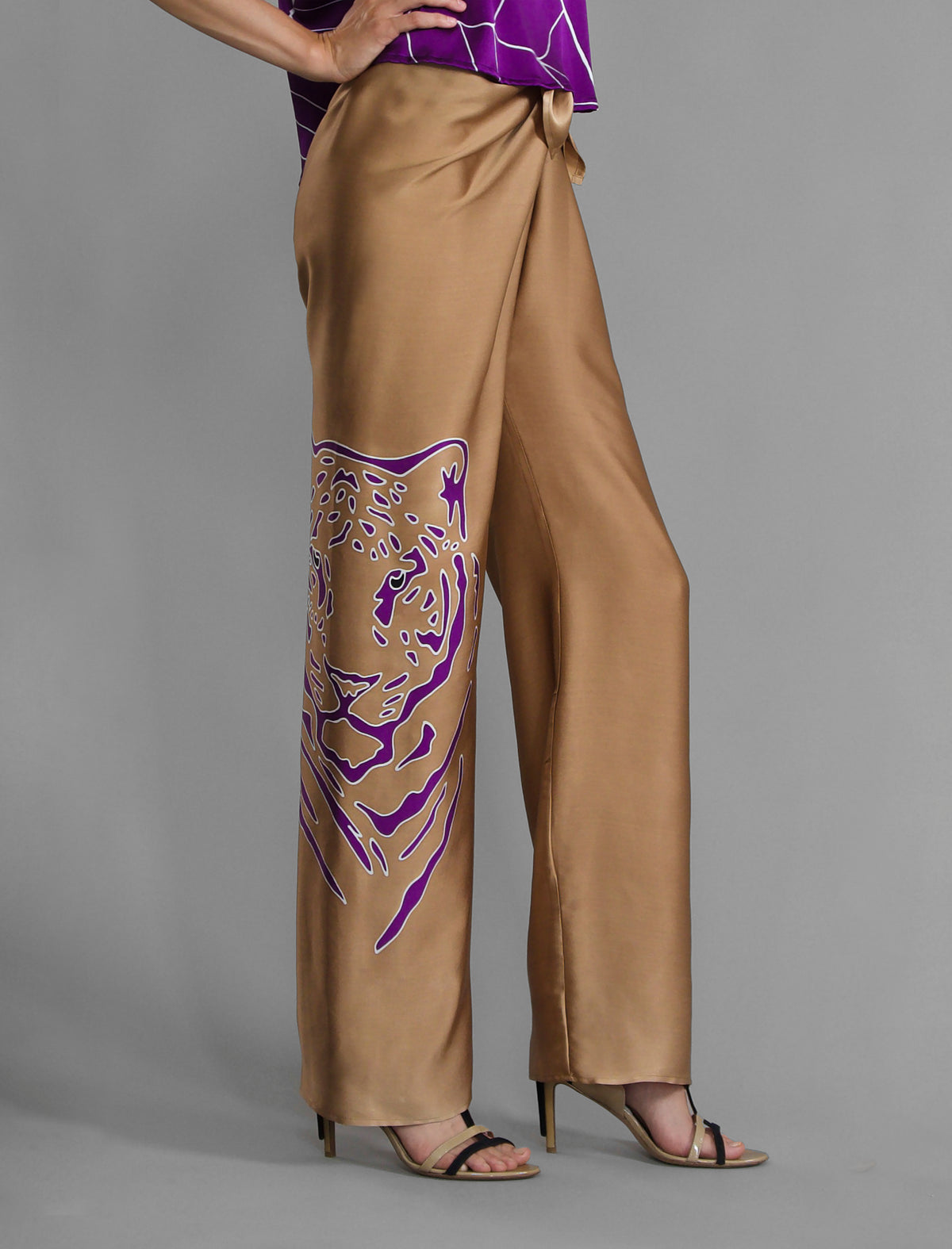Motif detail. Long silk pants in tobacco colour with purple tiger head batik motif, featuring a knot tie at the front and a slick relaxed silhouette.