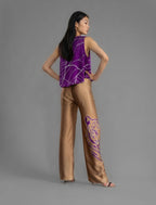Back view. Long silk pants in tobacco colour with purple tiger head batik motif, featuring a knot tie at the front and a slick relaxed silhouette.