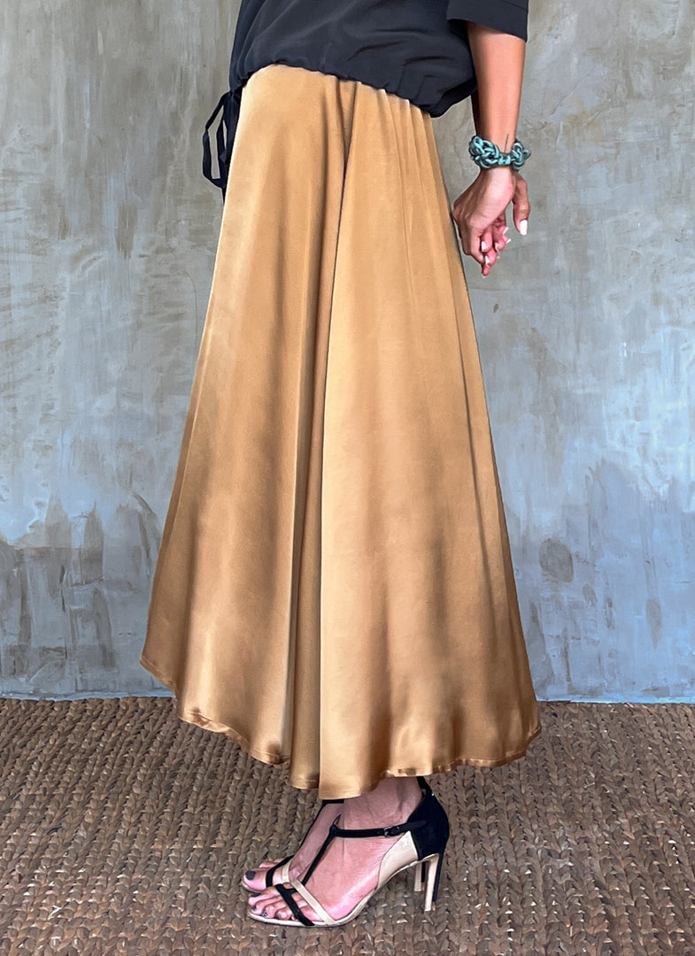 Side detail: Quarzia Aline Skirt, flowing curved hemline gathered panel across the back-handcrafted from premium rayon. Plain Cashew-color crafted by artisans made in Bali.