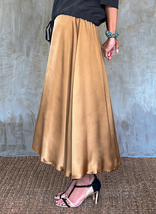 Side detail: Quarzia Aline Skirt, flowing curved hemline gathered panel across the back-handcrafted from premium rayon. Plain Cashew-color crafted by artisans made in Bali.