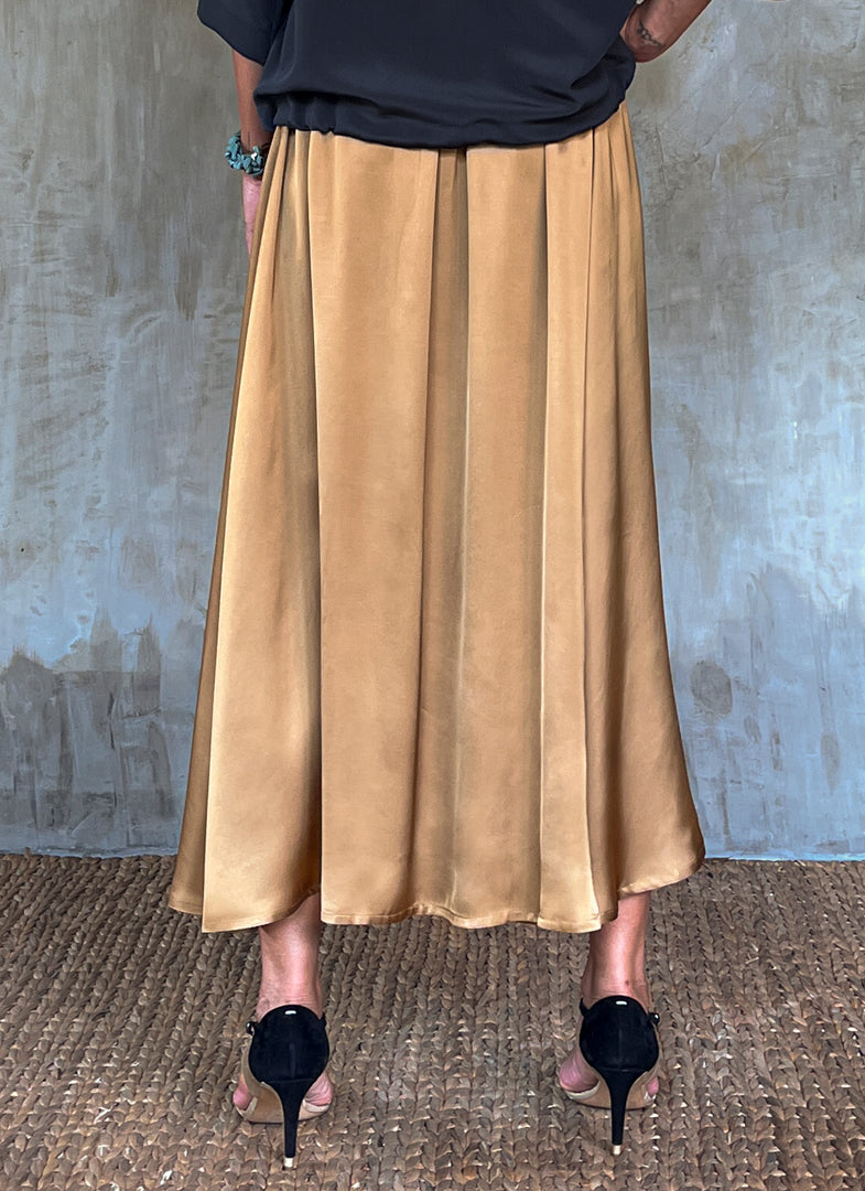 Back detail: Quarzia Aline Skirt, flowing curved hemline gathered panel across the back-handcrafted from premium rayon. Plain Cashew-color crafted by artisans made in Bali.