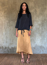 Load image into Gallery viewer, Quarzia Aline Skirt, flowing curved hemline gathered panel across the back-handcrafted from premium rayon. Plain Cashew-color crafted by artisans made in Bali.
