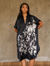 Load image into Gallery viewer,  Loose fit for the  Robi silk satin dress, with handpainted batik pattern of leafy branches in white on black background. The short sleeves and V-neckline add a subtle structure to the soft and fluid silhouette.


