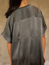 Load image into Gallery viewer, Back detail: loose fit for the  Robi silk satin dress, with handpainted batik pattern of leafy branches in beige on grey background only in the front. The short sleeves , V-neckline  and 2 darts on the back body add a subtle structure to the soft and fluid silhouette.



