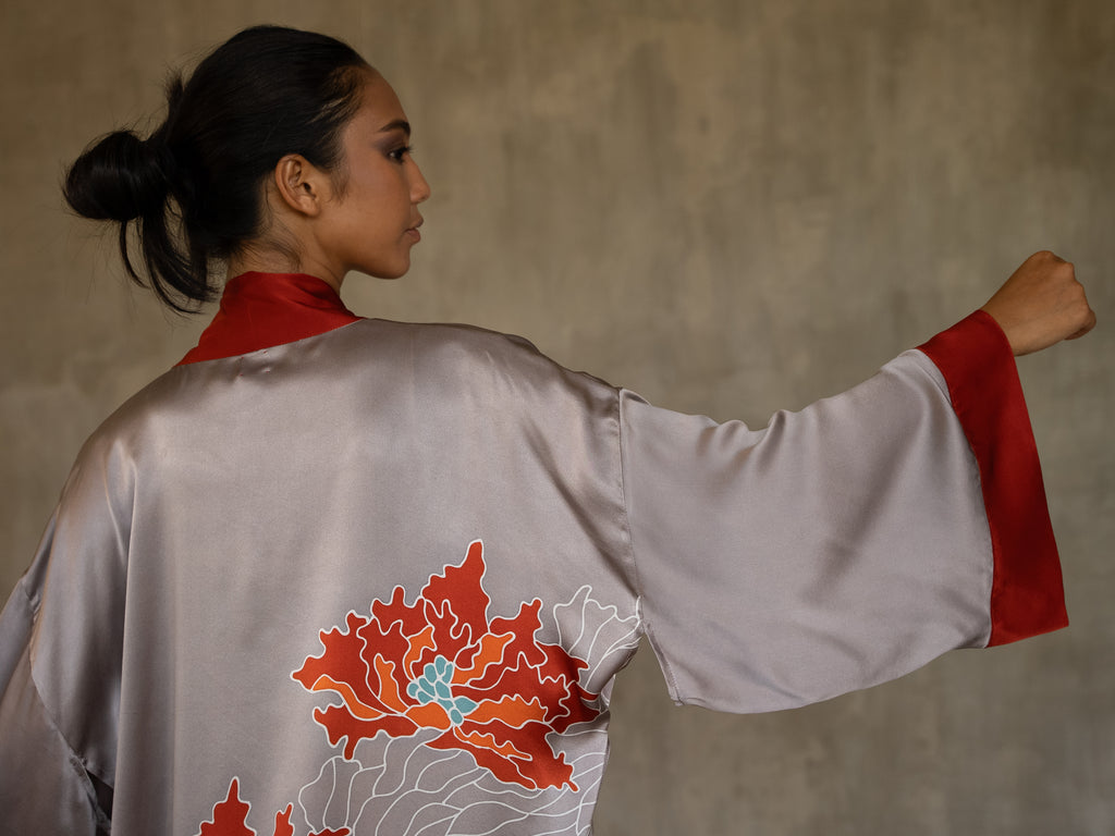 Quarzia signature Kimono has wide, flowing sleeves and it's handcrafted from pure silk satin. As Japanese style' kimono  it is open under the arms. A bold contrast color border on the cuffs and on the front, together with the same color silk belt, frame this elegant piece, ultimate in relaxed style, elegance and comfort. The batik pattern is inspired by the beauty of imperfection in nature.