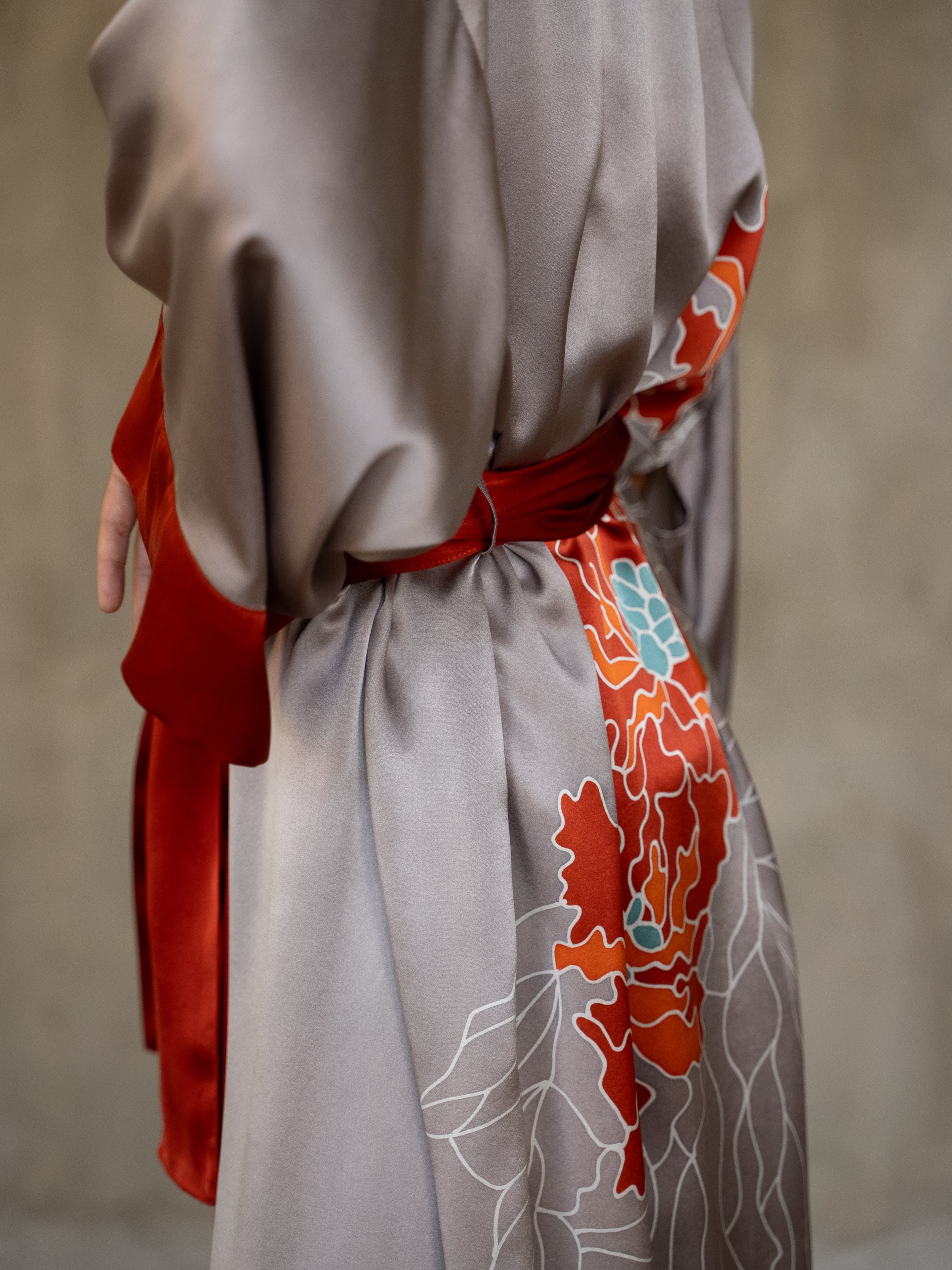 Side detail: Quarzia signature Kimono has wide, flowing sleeves and it's handcrafted from pure silk satin. As Japanese style' kimono  it is open under the arms. A bold contrast color border on the cuffs and on the front, together with the same color silk belt, frame this elegant piece, ultimate in relaxed style, elegance and comfort. The batik pattern is inspired by the beauty of imperfection in nature.