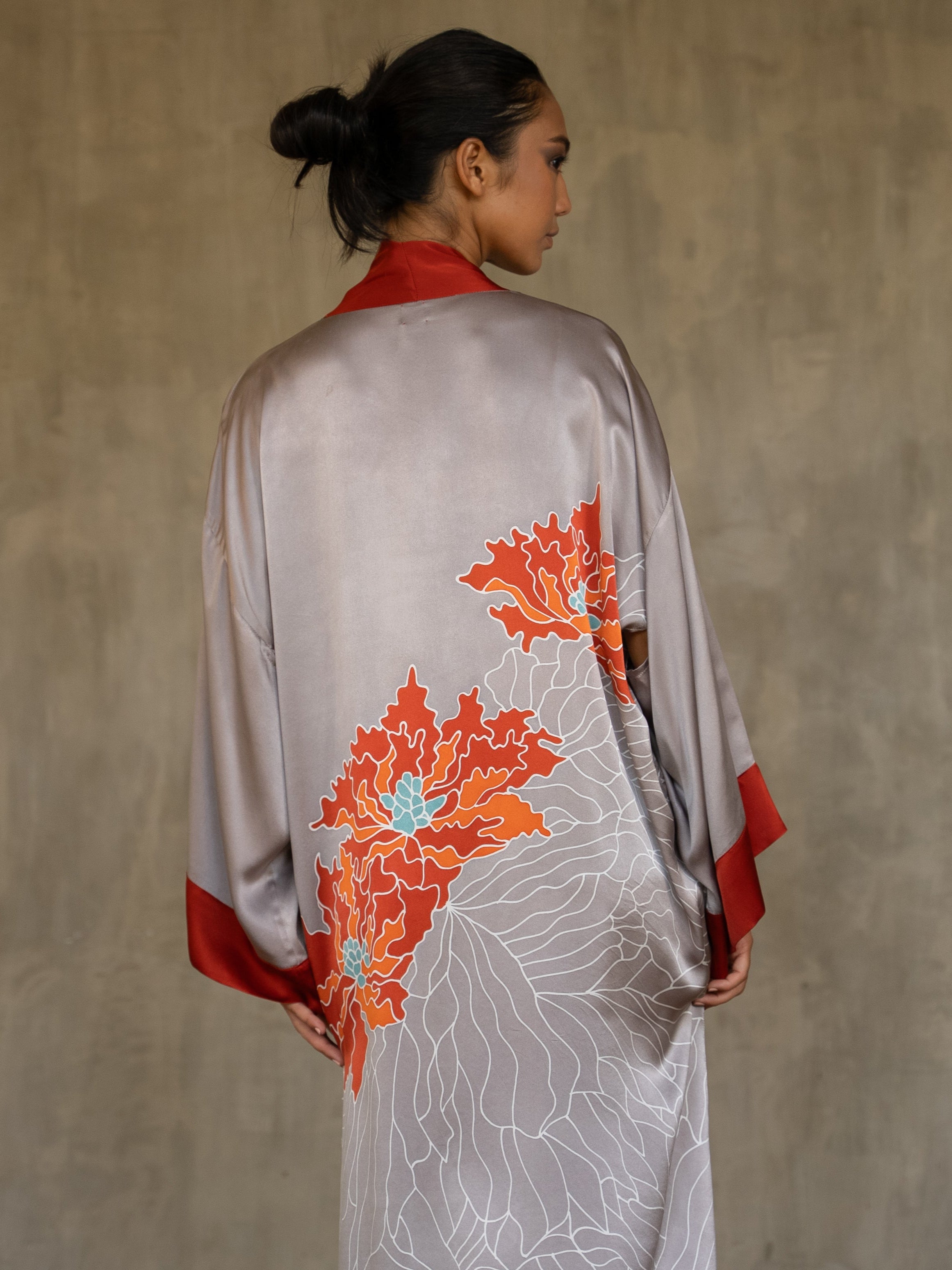 Back detail: Quarzia signature Kimono has wide, flowing sleeves and it's handcrafted from pure silk satin. As Japanese style' kimono  it is open under the arms. A bold contrast color border on the cuffs and on the front, together with the same color silk belt, frame this elegant piece, ultimate in relaxed style, elegance and comfort. The batik pattern is inspired by the beauty of imperfection in nature.