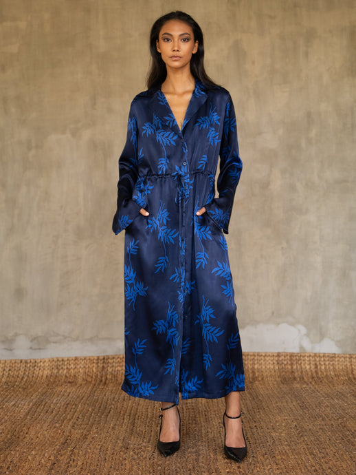 Hand-crafted in glossy pure silk, this jacket' neck-line dress it has elegant, structured trumpet cuffs,   discreet pockets and waist drawstring add to the sophistication and comfort. Pure silk decorated by hand with our leafy pattern Dedaun, in rich blue tones.