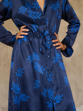 Load image into Gallery viewer, Front detail: Hand-crafted in glossy pure silk, this jacket&#39; neck-line dress it has elegant, structured trumpet cuffs,   discreet pockets and waist drawstring add to the sophistication and comfort. Pure silk decorated by hand with our leafy pattern Dedaun, in rich blue tones.
