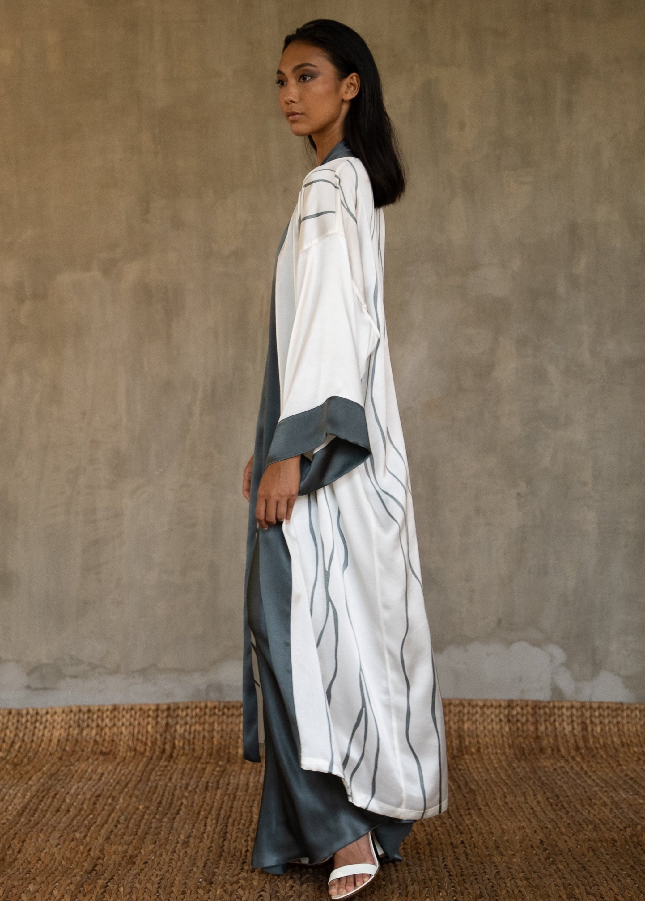 Side detail: Quarzia signature Kimono has wide, flowing sleeves and it's handcrafted from pure silk satin. As Japanese style' kimono  it is open under the arms, and there's a bold border on the cuff sand on the front. A beautiful silk belt frame this elegant piece, ultimate in relaxed style, elegance and comfort. The batik pattern is inspired by Kintsugi Japanese technique to fix the broken ceramics.