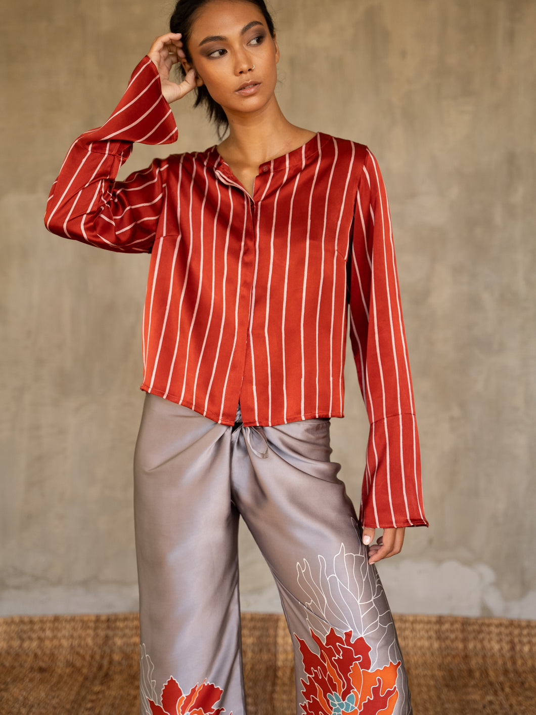 Quarzia artisanal short jacket in red color and white stripes wear on a silk long pant with floral decoration grey/pink. Made in Bali.