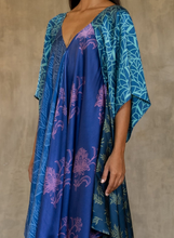 Load image into Gallery viewer, Front detail: the  silk satin blue Ally dress is a celebration of modern batik patterns. Multiple designs, inspired by nature, are hand-crafted on silk in various hues of blue. The generous silhouette will suite all sizes.
