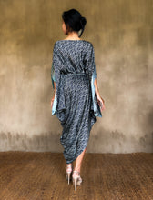 Load image into Gallery viewer, Back detail: asymmetric long Jogya silk dress with a &quot;Deco&quot; pattern in grey and dark blue colors. The dress features a loose fit with a belt and has a subtle asymmetrical design. Steel grey border define the kimono-like sleeves. Luxury resort-wear in silk batik made in Bali. 

