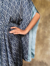 Load image into Gallery viewer, Sleeve detail: Rich silk border in contrast grey color on the kimono-like sleeves. Asymmetric long Jogya silk dress with a &quot;Deco&quot; pattern in grey and dark blue colors. The dress features a loose fit with a belt and has a subtle asymmetrical design. Steel grey border define the kimono-like sleeves. Luxury resort-wear in silk batik made in Bali. 
