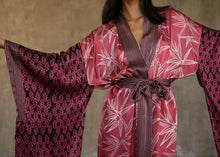 Load image into Gallery viewer, front detail: Quarzia&#39;s closest take on japanese Kimono&#39; style, glossy batik patterned silk satin with &quot;Furisode&quot; long-hanging sleeves. Formal robe in graphic floral patterns, in pink/white/black colors. Cuffs, front border and belt all in contrast pattern define this timeless piece. 
