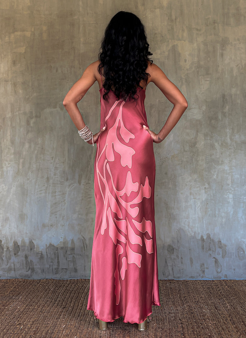 Back detail: Silk satin handcrafted long spaghetti dress in pink with maxi foliage pattern front and back. Bias cut dress with low V-neckline.