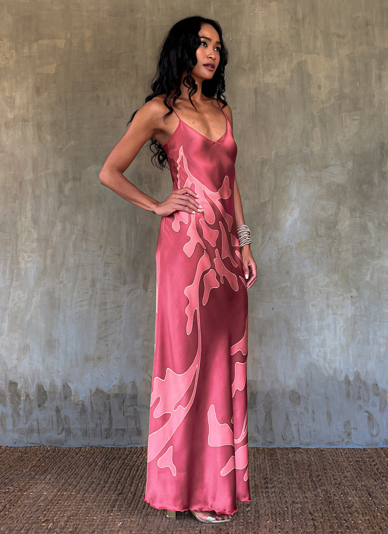 side detail:Silk satin handcrafted long spaghetti dress in pink with maxi foliage pattern front and back. Bias cut dress with low V-neckline.