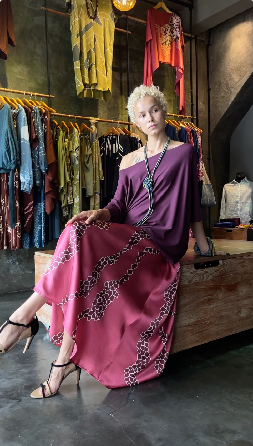 Woman in a purple silk top and hand-painted pink silk skirt, seated in a Quarzia store